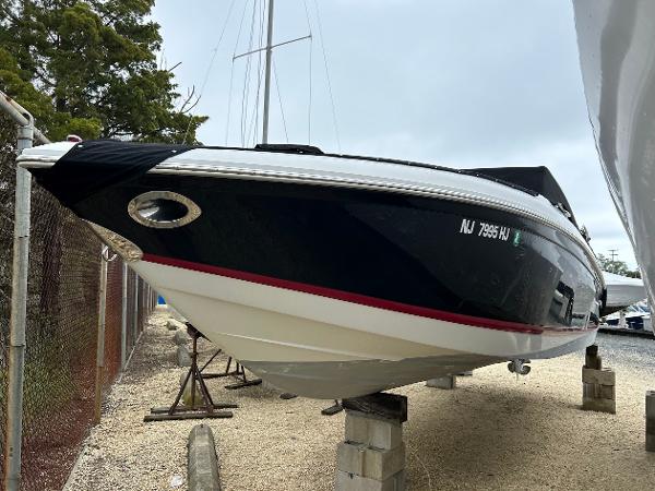 Cobalt 262 2010 Cobalt 262 boat on blocks, black hull with red stripe, parked outdoors.