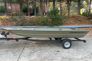 Tracker Grizzly 1648 Utility 2026 Tracker Grizzly 1648 Utility boat on trailer, parked outdoors near trees.
