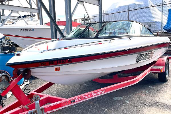 Malibu Response LX 1999 Malibu Response LX boat on a red trailer in a marina setting.
