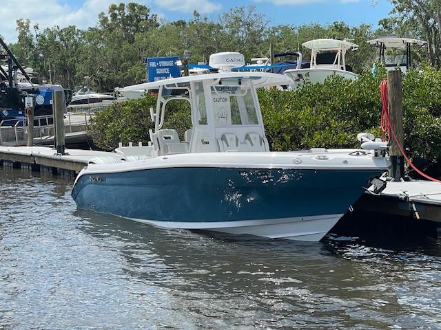 Century 2900 Cc 2022 Century 2900 CC boat docked at marina, surrounded by lush greenery and calm waters.