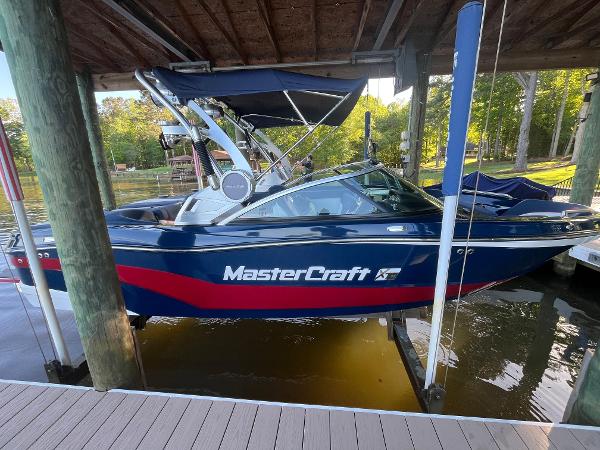 MasterCraft XT21 2018 MasterCraft XT21 boat docked under a wooden canopy on a sunny day.