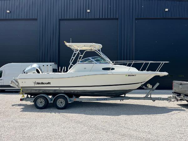 Wellcraft WALK AROUND 2000 Wellcraft WALK AROUND boat on trailer, parked outdoors near a black building.