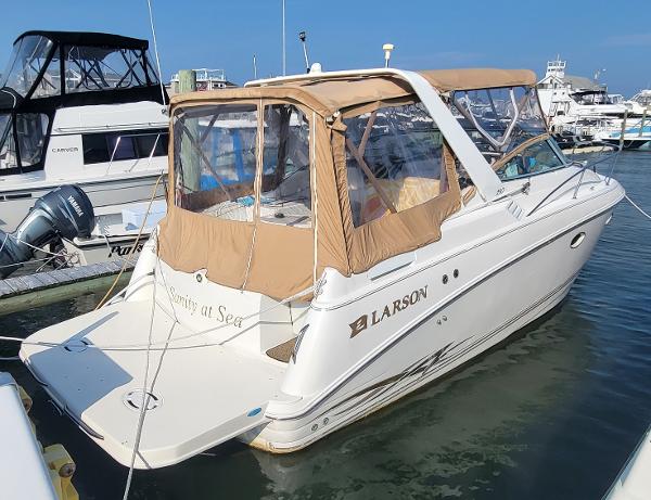 Larson Cabrio 290 2000 Larson Cabrio 290 boat docked in marina with tan canopy.
