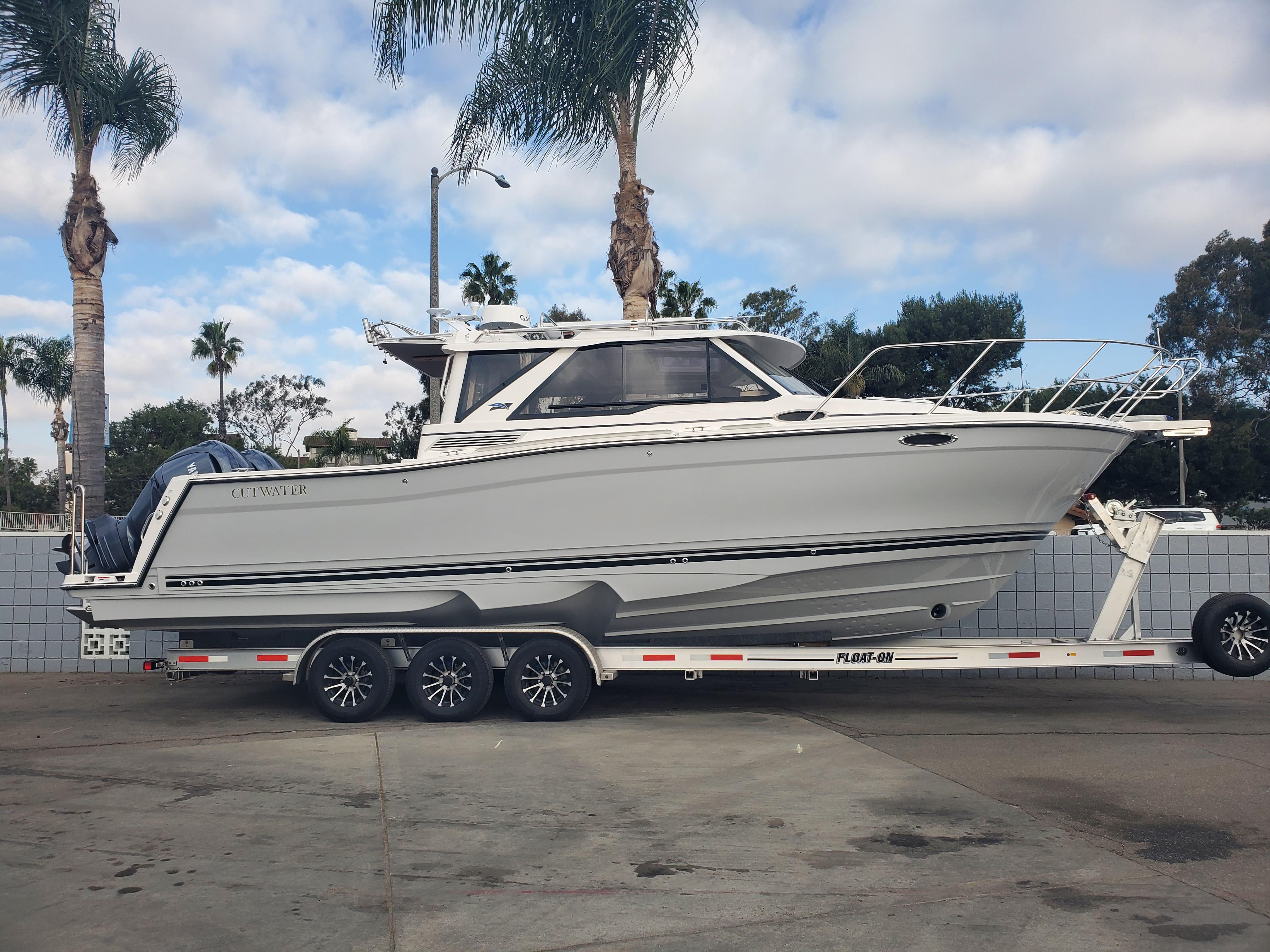 Cutwater C-288 Coupe 2025 Cutwater C-288 Coupe boat on trailer, parked outdoors with palm trees.
