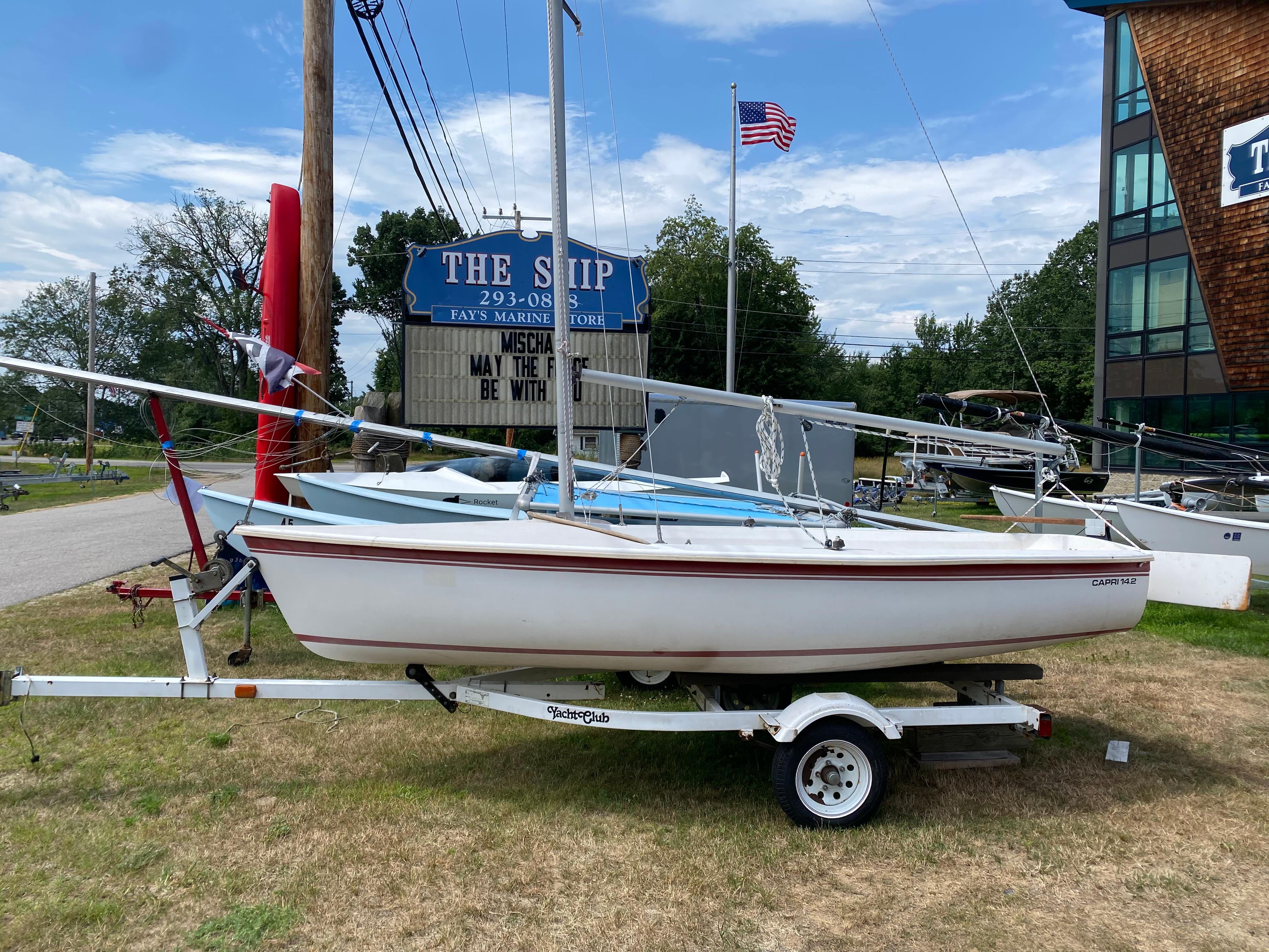 Catalina CAPRI 14.2 1986 Catalina Capri 14.2 sailboat on trailer at marina with American flag.