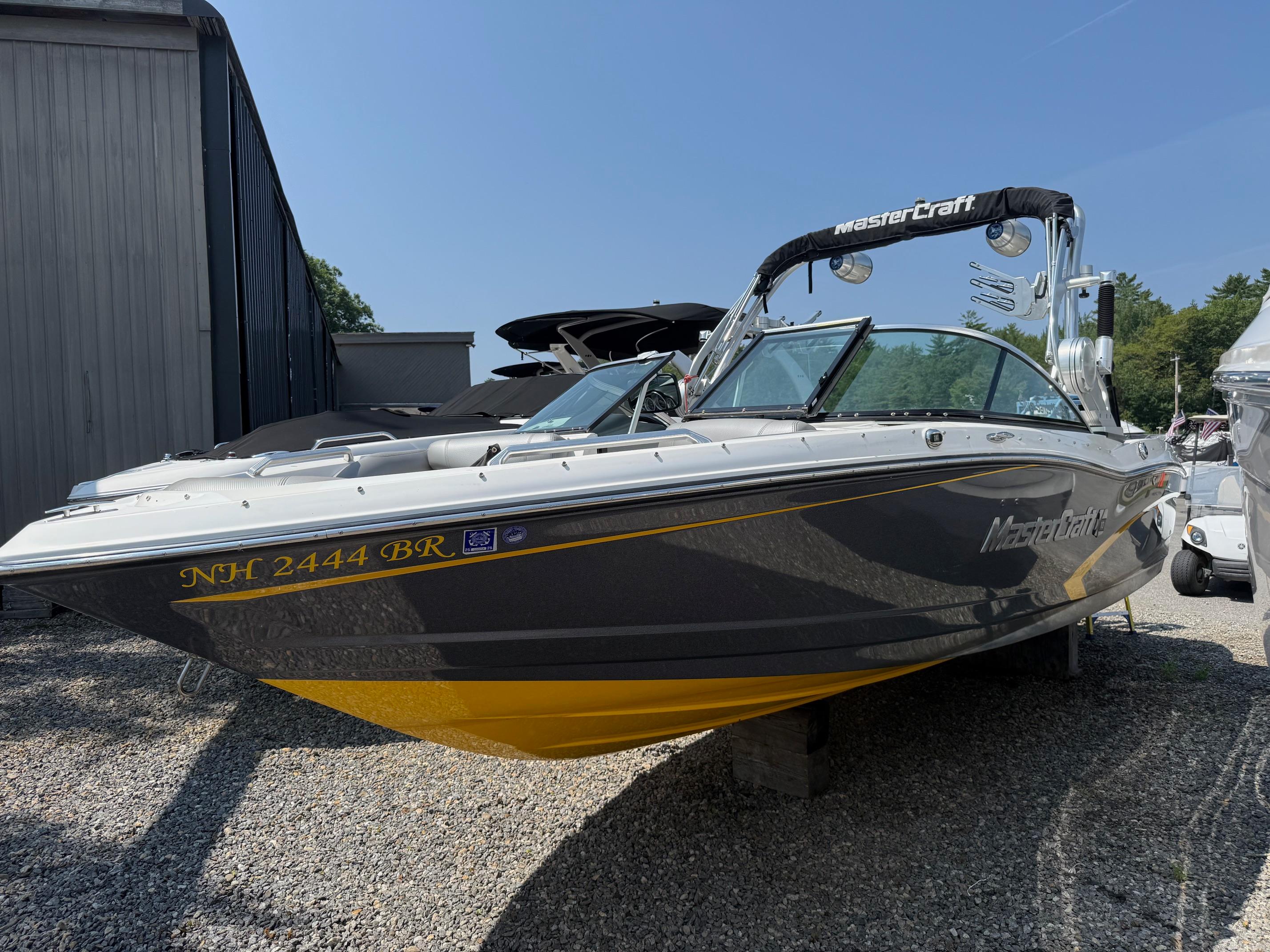 MasterCraft X10 2015 MasterCraft X10 boat with sleek design, parked on gravel near a building.