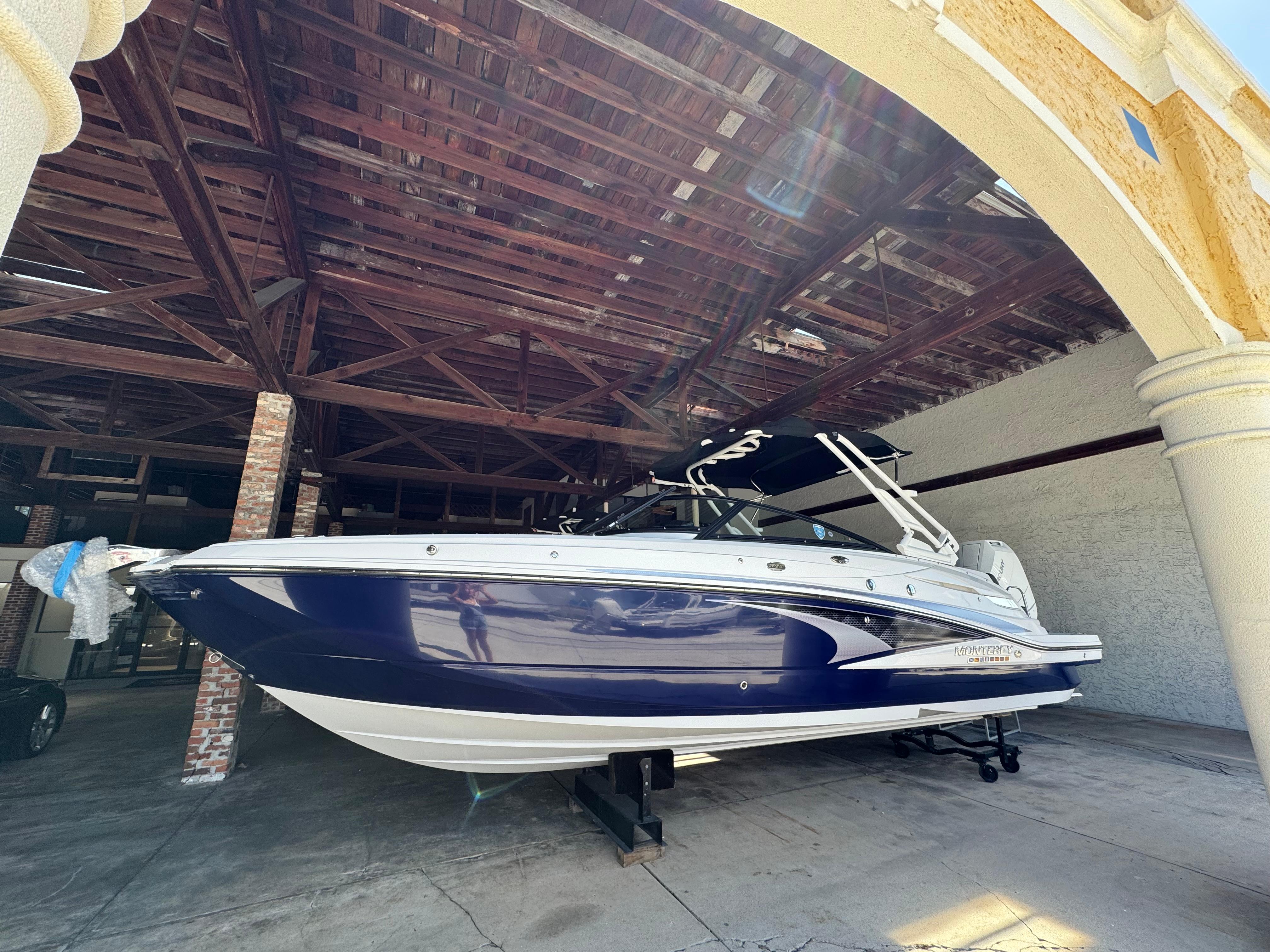 Monterey M-65 2024 Monterey M-65 boat in a covered storage area, showcasing sleek design and blue hull.
