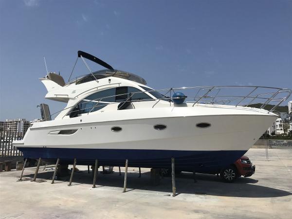 Galeon 390 Fly 2007 Galeon 390 Fly yacht on stands, white hull, blue bottom, clear sky background.