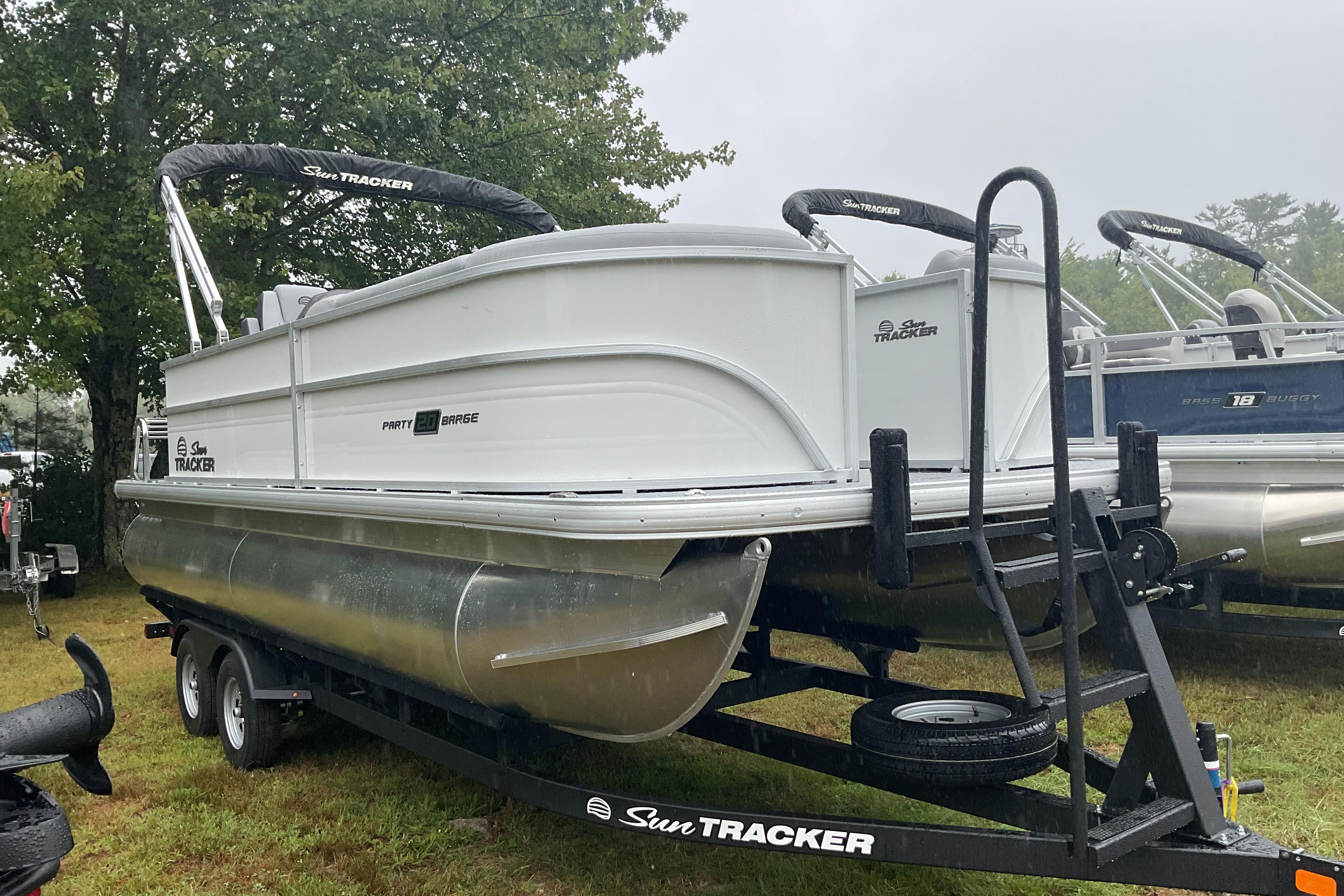Sun Tracker PB 20 DLX 2026 Sun Tracker PB 20 DLX pontoon boat on trailer, parked outdoors.