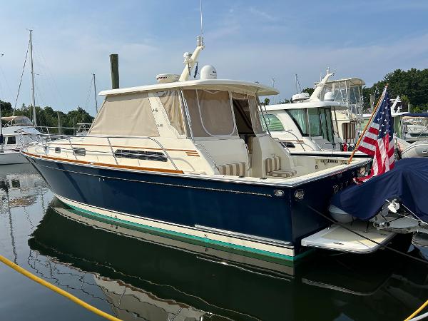 Sabre Hardtop Express 2009 Sabre Hardtop Express boat docked with American flag, blue hull, and beige canopy.