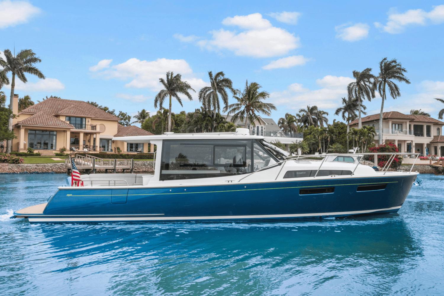 MJM 42 2024 MJM 42 yacht cruising on a sunny day near luxury waterfront homes.