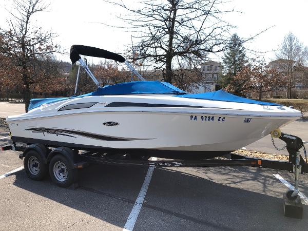 Sea Ray 195 Sport 2011 Sea Ray 195 Sport boat on trailer, parked in a lot with trees in the background.