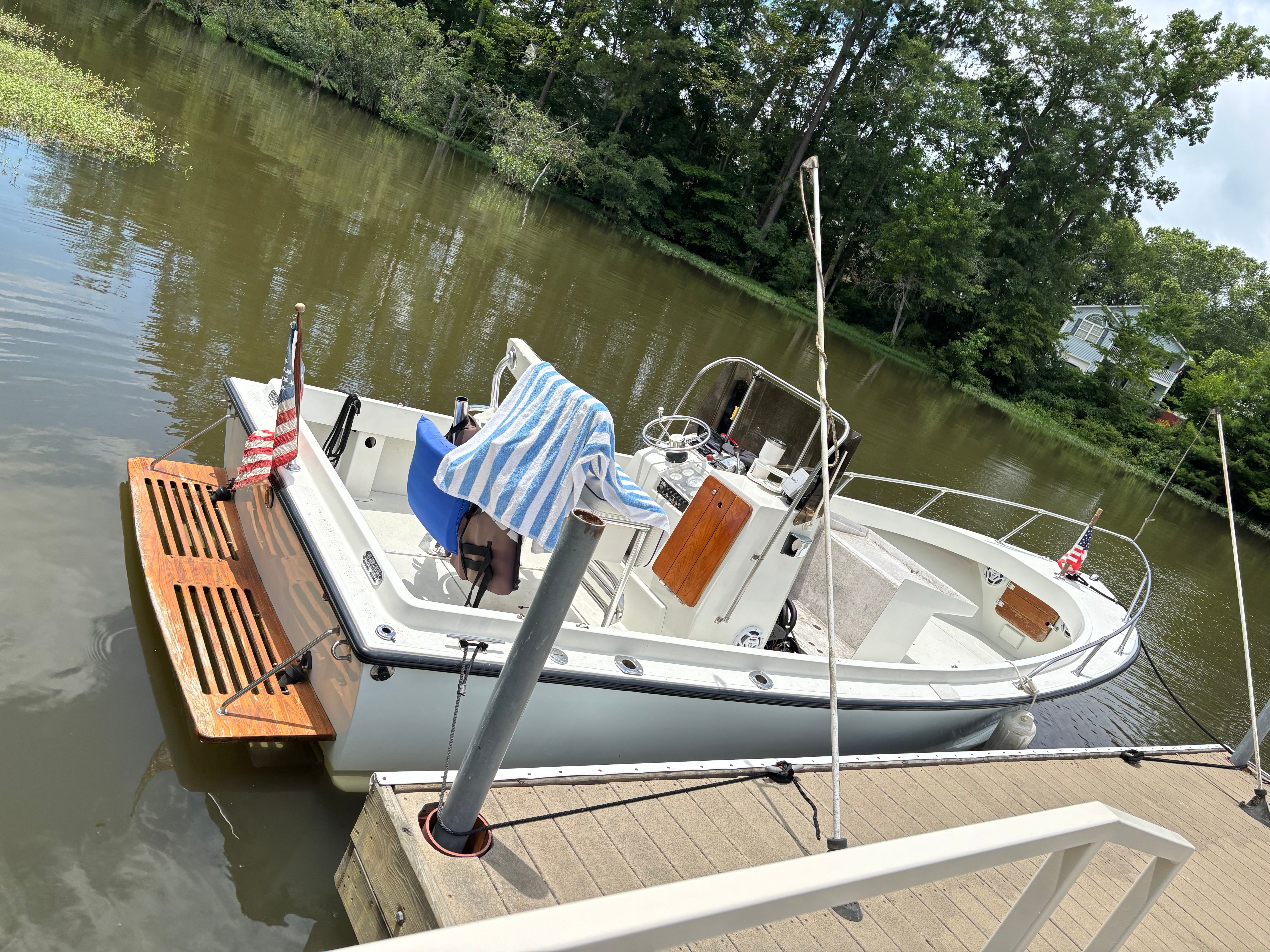 Shamrock Open 20 1986 Shamrock Open 20 boat docked on a calm river with lush greenery.