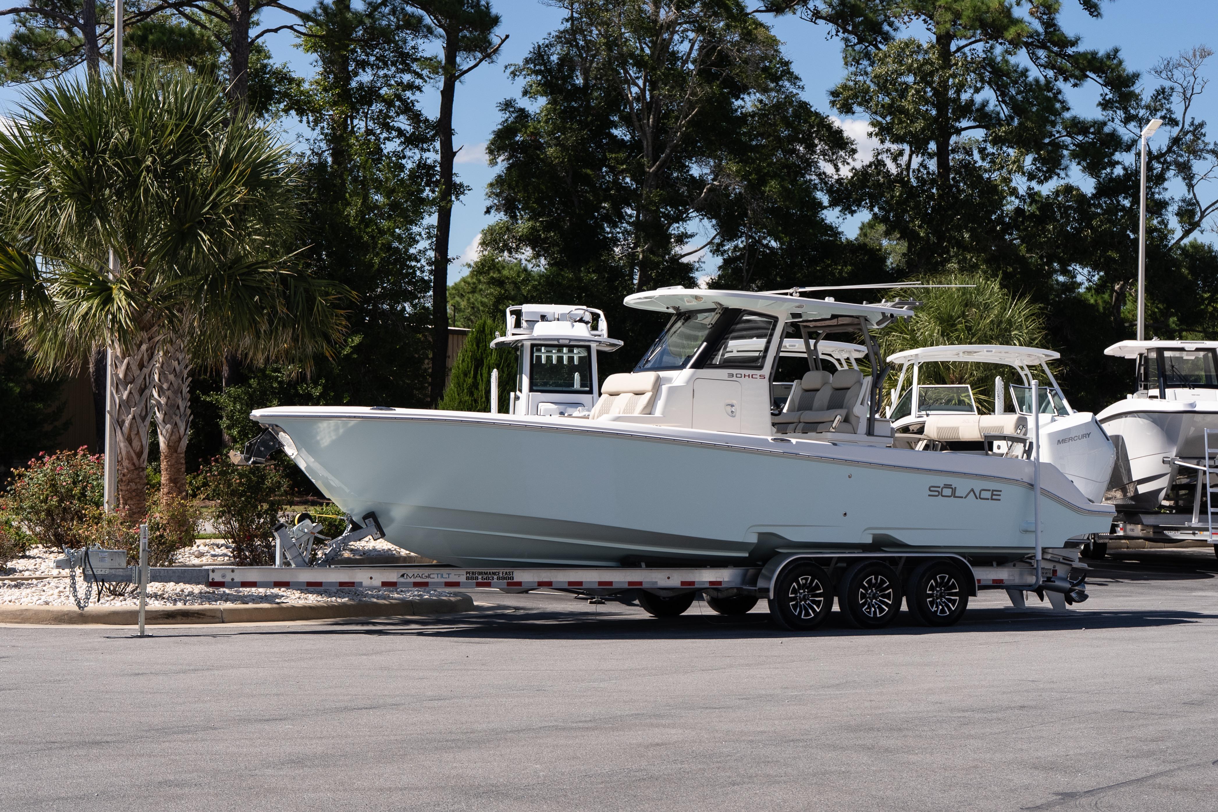 Solace 30 HCS 2026 Solace 30 HCS boat on trailer, parked outdoors with trees in background.