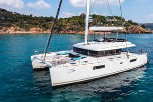 Lagoon 560 S2 2014 Lagoon 560 S2 catamaran anchored in clear blue water near a rocky coastline.