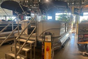 Sun Tracker Party Barge 20 DLX 2026 Sun Tracker Party Barge 20 DLX pontoon boat displayed indoors with promotional signage.