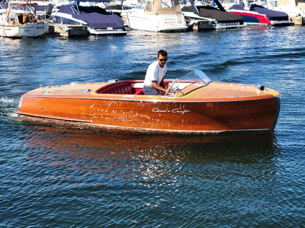 Chris-Craft Riviera 16 1951 Chris-Craft Riviera 16 classic wooden boat on water with man at helm.