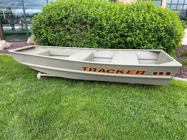 Tracker Grizzly 1036 Utility 2025 Tracker Grizzly 1036 Utility boat on grass, near green bushes.