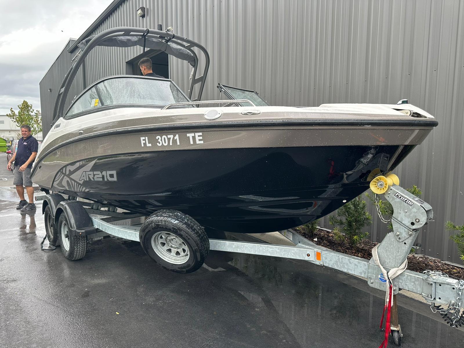 Yamaha Boats AR210 2022 Yamaha AR210 boat on trailer, parked outside a building.