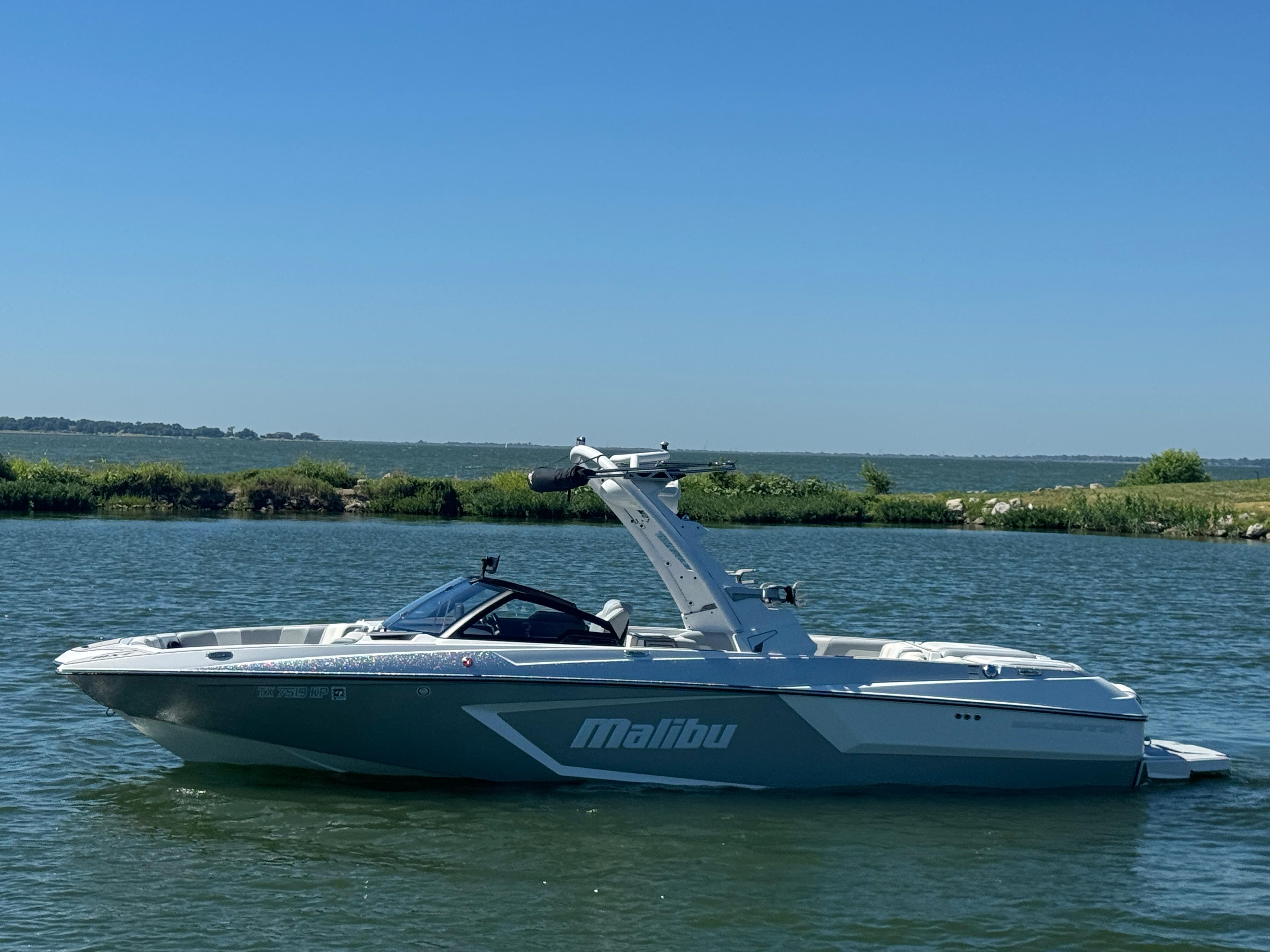 Malibu Wakesetter 24 MXZ 2022 Malibu Wakesetter 24 MXZ boat on calm water under clear blue sky.