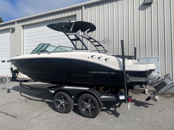 Chaparral 21 Surf 2022 Chaparral 21 Surf boat on trailer, parked outside a metal building.