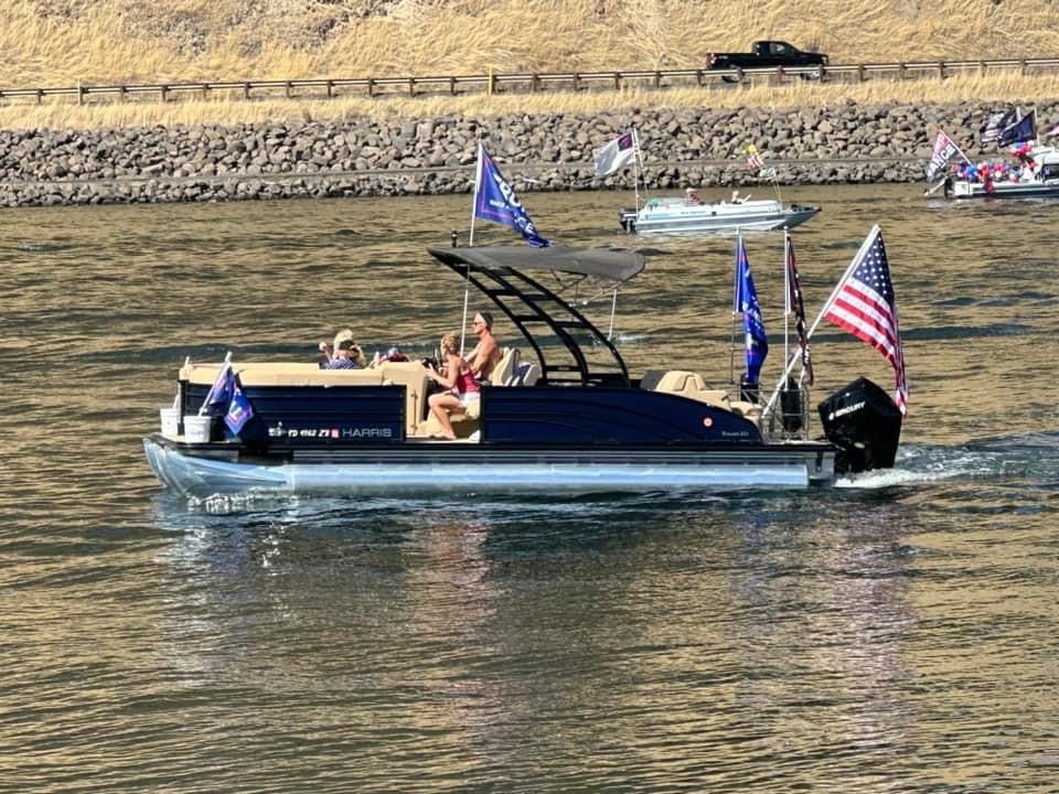 Harris sun Harris Sun 2021 pontoon boat with flags on a sunny lake.