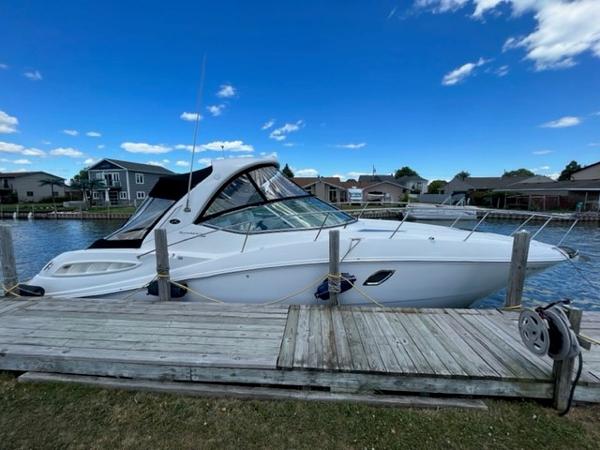 Sea Ray 330 Sundancer 2009 Sea Ray 330 Sundancer docked by waterfront homes under a clear blue sky.