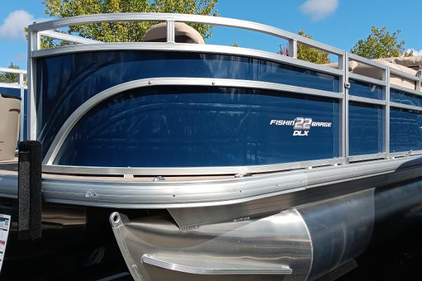 Sun Tracker Fishin' Barge 22 DLX 2024 Sun Tracker Fishin' Barge 22 DLX pontoon boat, blue exterior, docked outdoors.