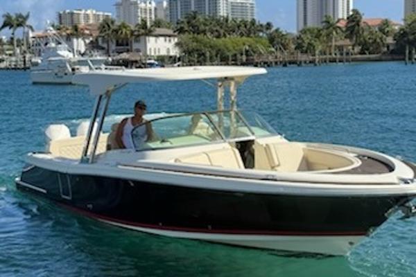 Chris-Craft Calypso 30 2020 Chris-Craft Calypso 30 boat cruising on clear blue water near a cityscape.