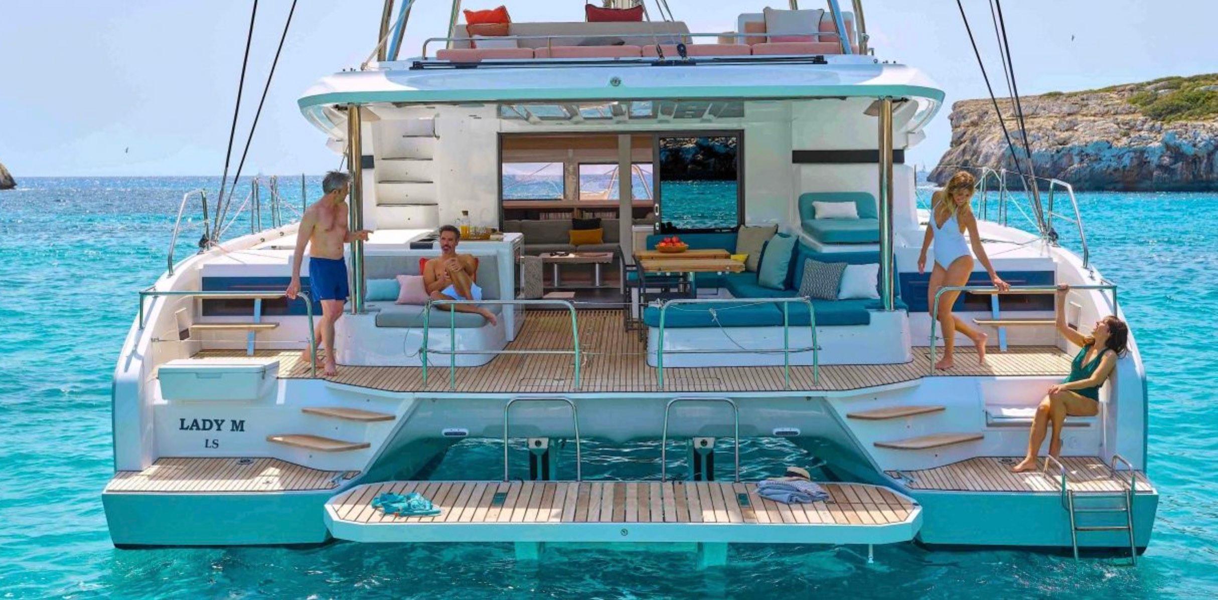 Lagoon 55 2025 Lagoon 55 yacht with people relaxing on deck in clear blue water.