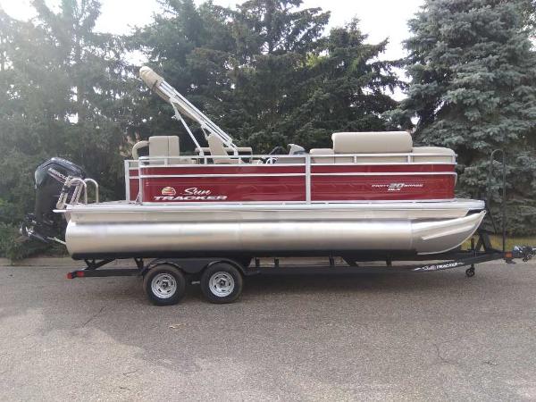 Sun Tracker Party Barge 20 DLX 2024 Sun Tracker Party Barge 20 DLX pontoon boat on trailer, parked outdoors.