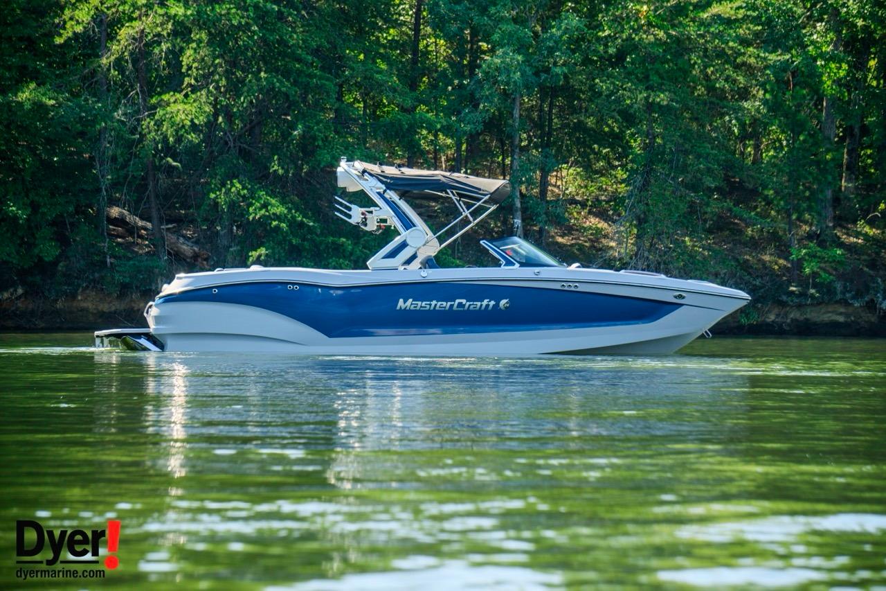 MasterCraft X24 2024 MasterCraft X24 boat on a serene lake with lush green forest backdrop.