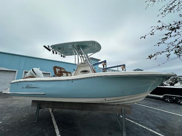 Pioneer 222 Islander 2025 Pioneer 222 Islander boat with blue hull and T-top in a parking lot.