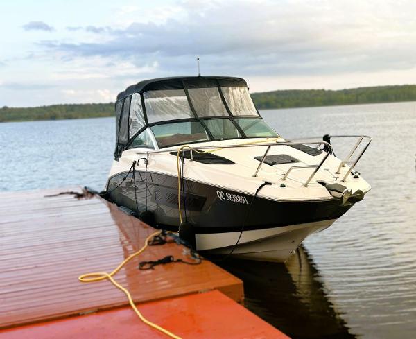 Four Winns V255 2017 Four Winns V255 boat docked on a calm lake with a scenic background.