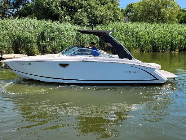 Cobalt R5 2020 Cobalt R5 boat cruising on a calm river with lush greenery in the background.