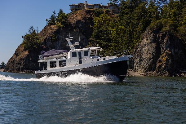 American Tug 435 2026 American Tug 435 cruising near rocky shoreline with trees.