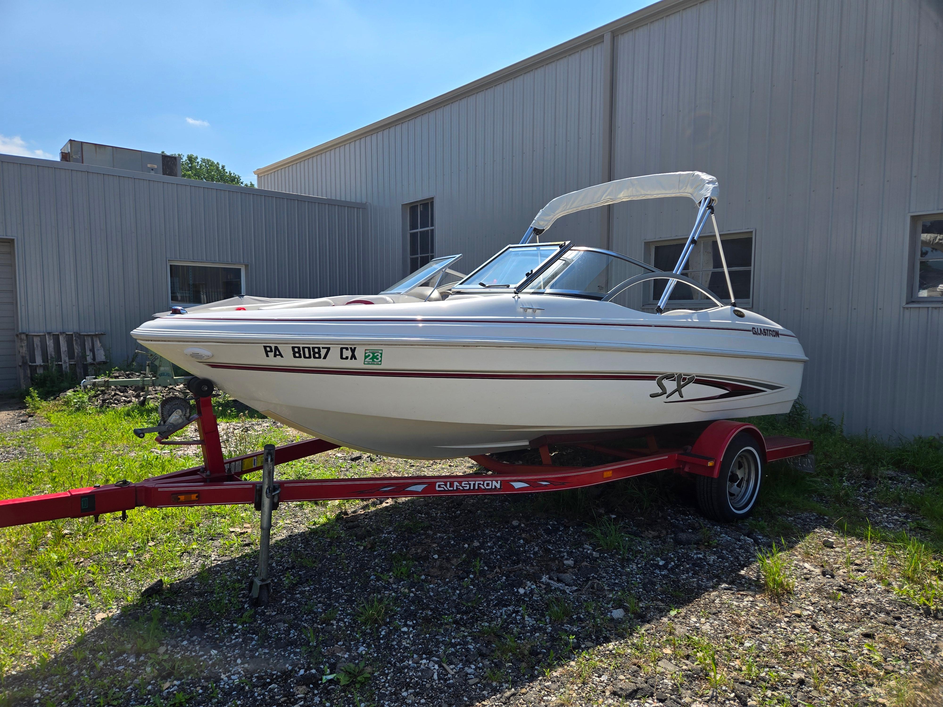 Glastron 175 Sx 2005 Glastron 175SX boat on red trailer, parked outdoors near a building.