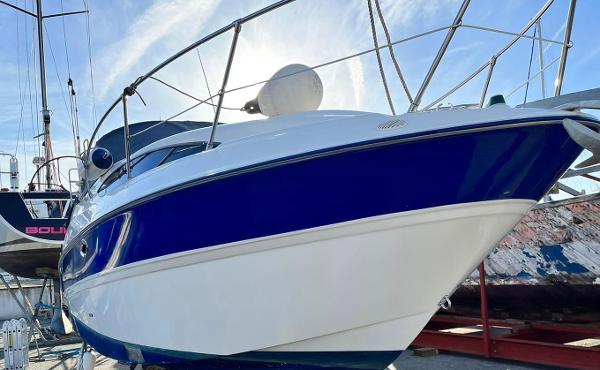 Bayliner 245 CIERA 2006 Bayliner 245 CIERA boat with blue and white hull, docked under clear sky.
