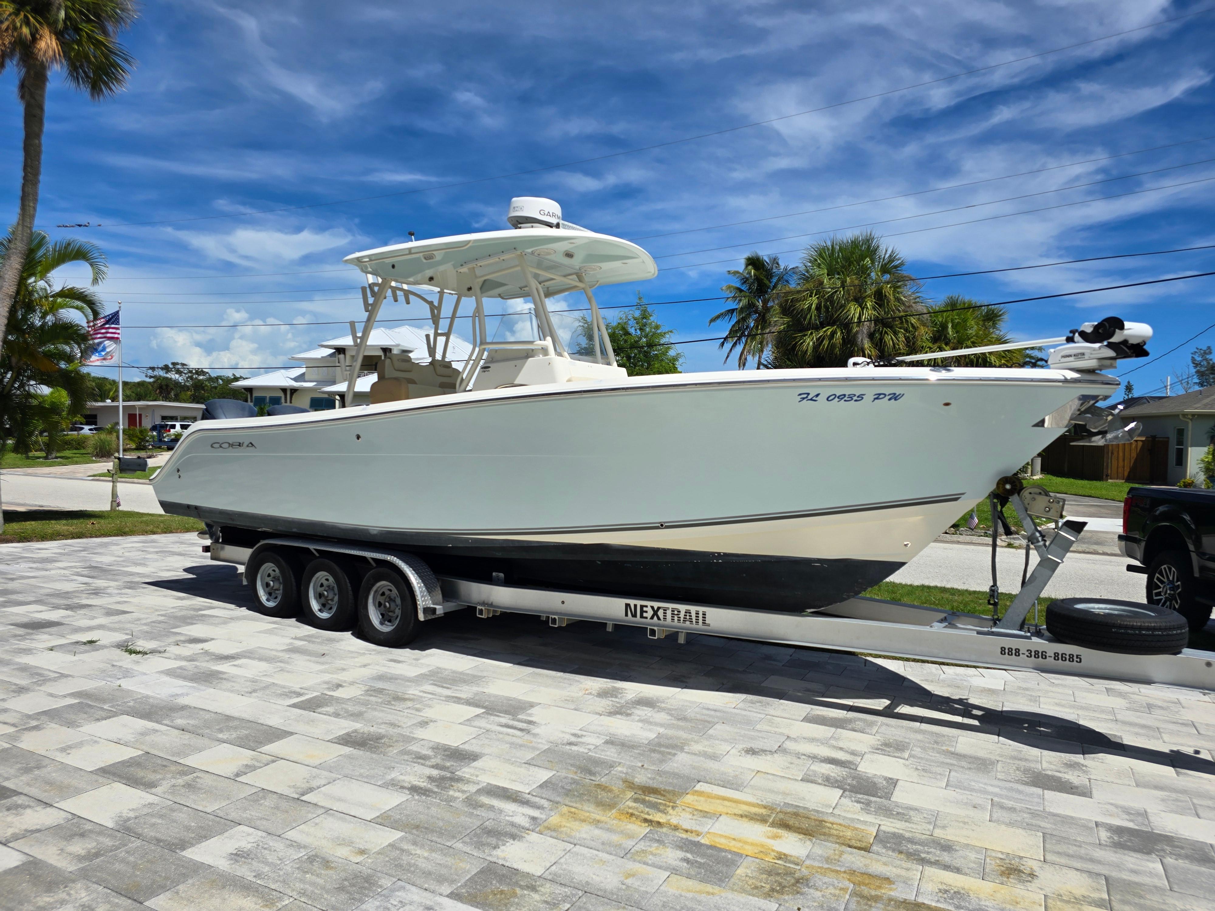 Cobia 296 Center Console 2015 Cobia 296 Center Console boat on trailer, parked in a driveway under a clear blue sky.