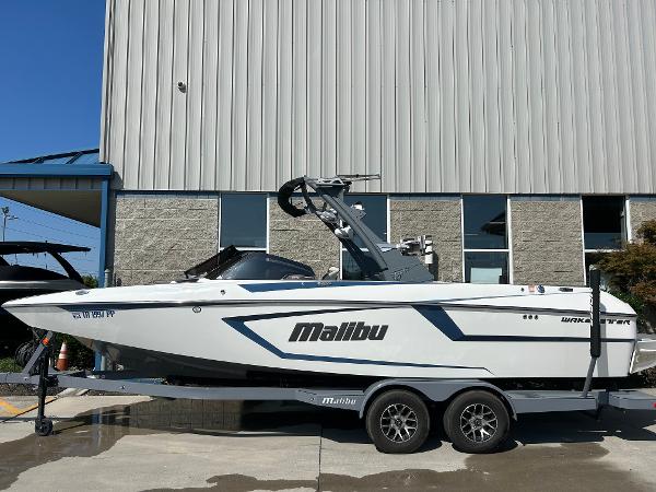Malibu Wakesetter 24 MXZ 2021 Malibu Wakesetter 24 MXZ boat on trailer, parked outside a building.