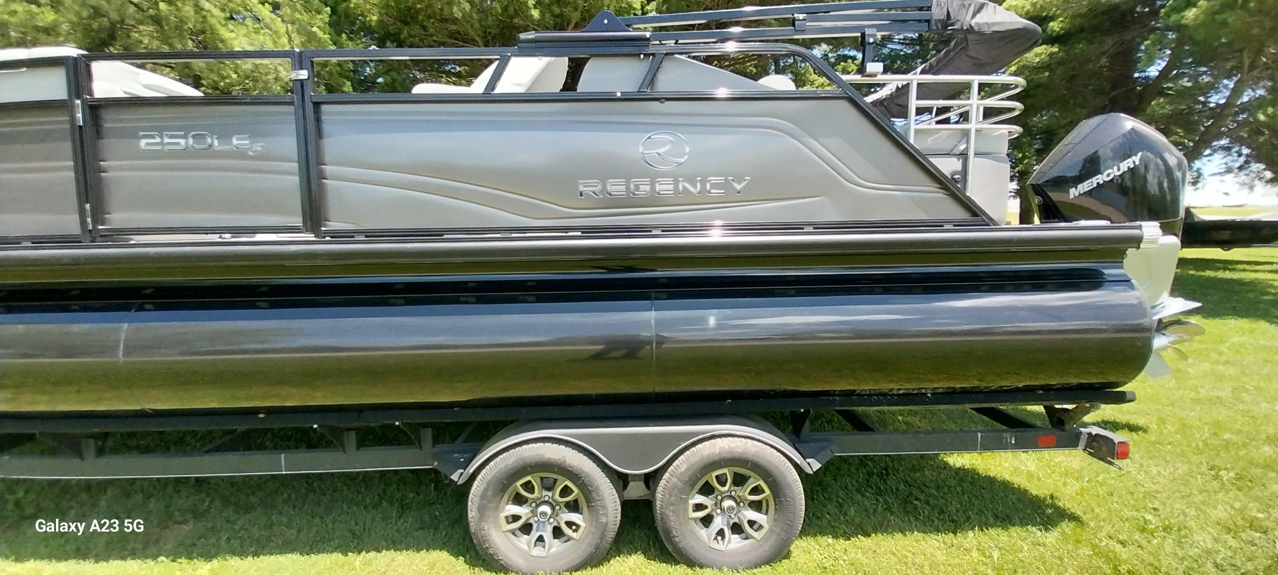 Regency 250 LE3 Sport 2023 Regency 250 LE3 Sport pontoon boat on trailer, side view, outdoors.