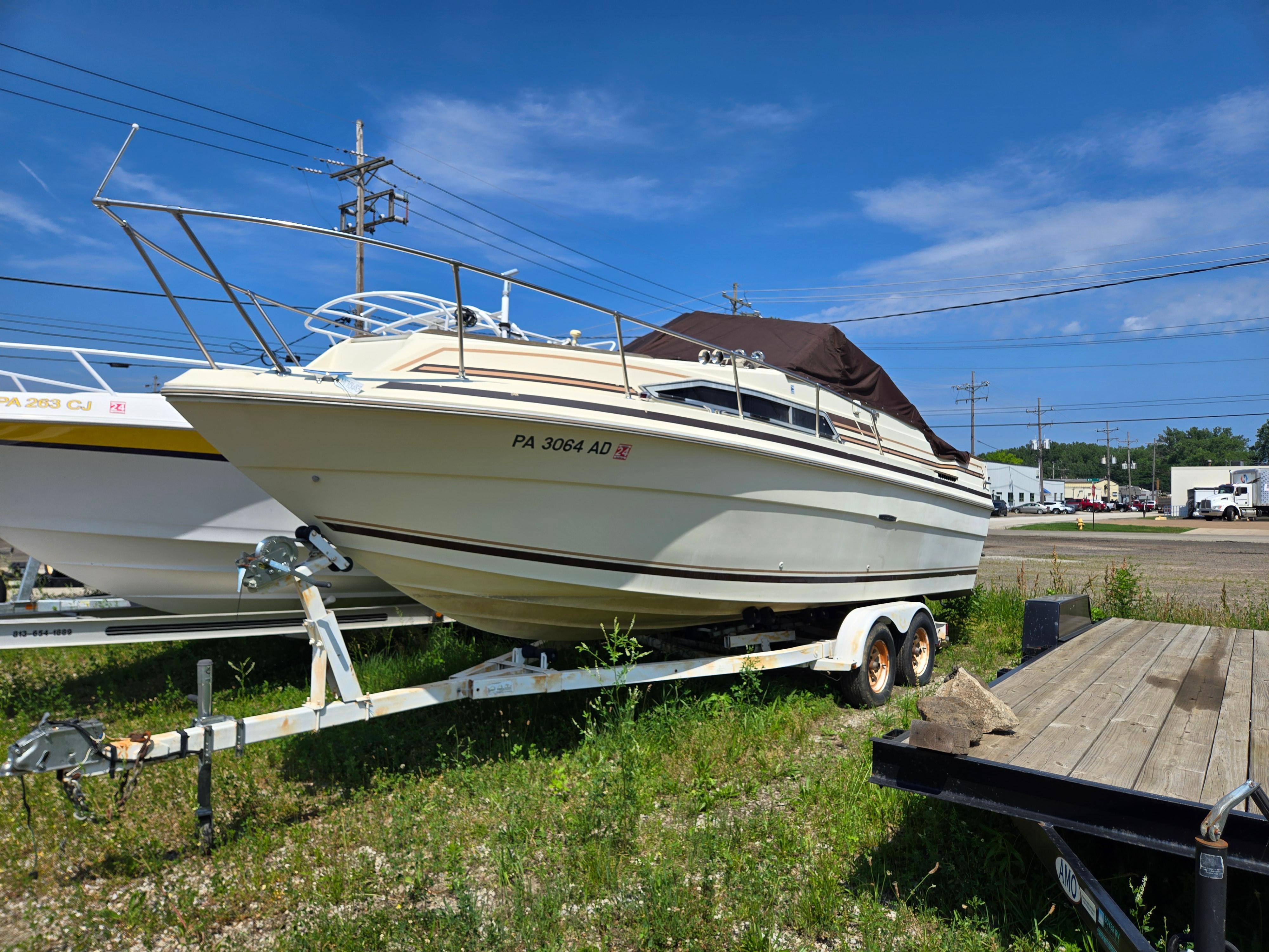 Sea Ray Weekender 1983 Sea Ray Weekender boat on trailer, parked outdoors under clear blue sky.