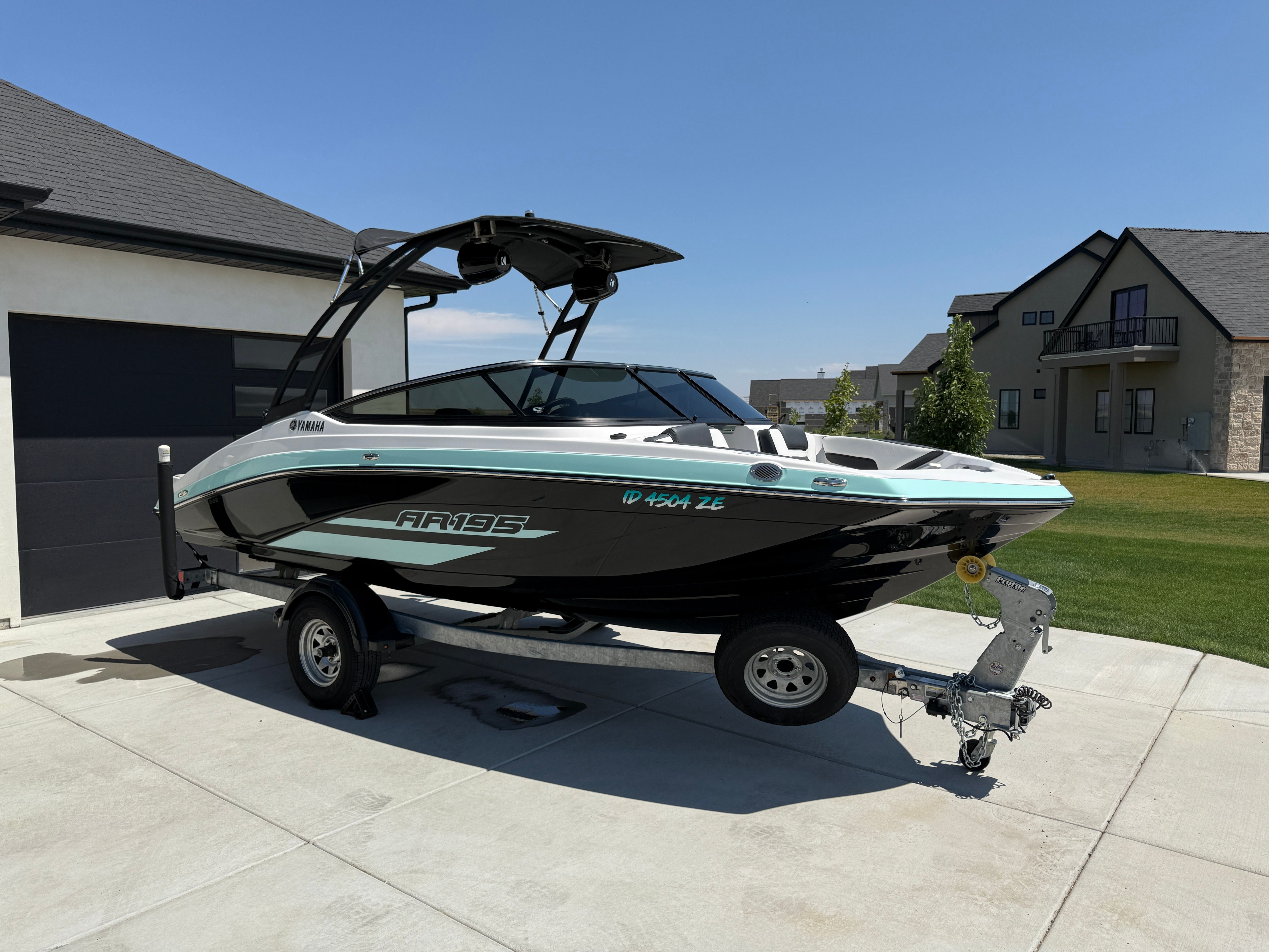 Yamaha Boats AR195 2023 Yamaha AR195 boat on trailer in driveway, modern homes in background.