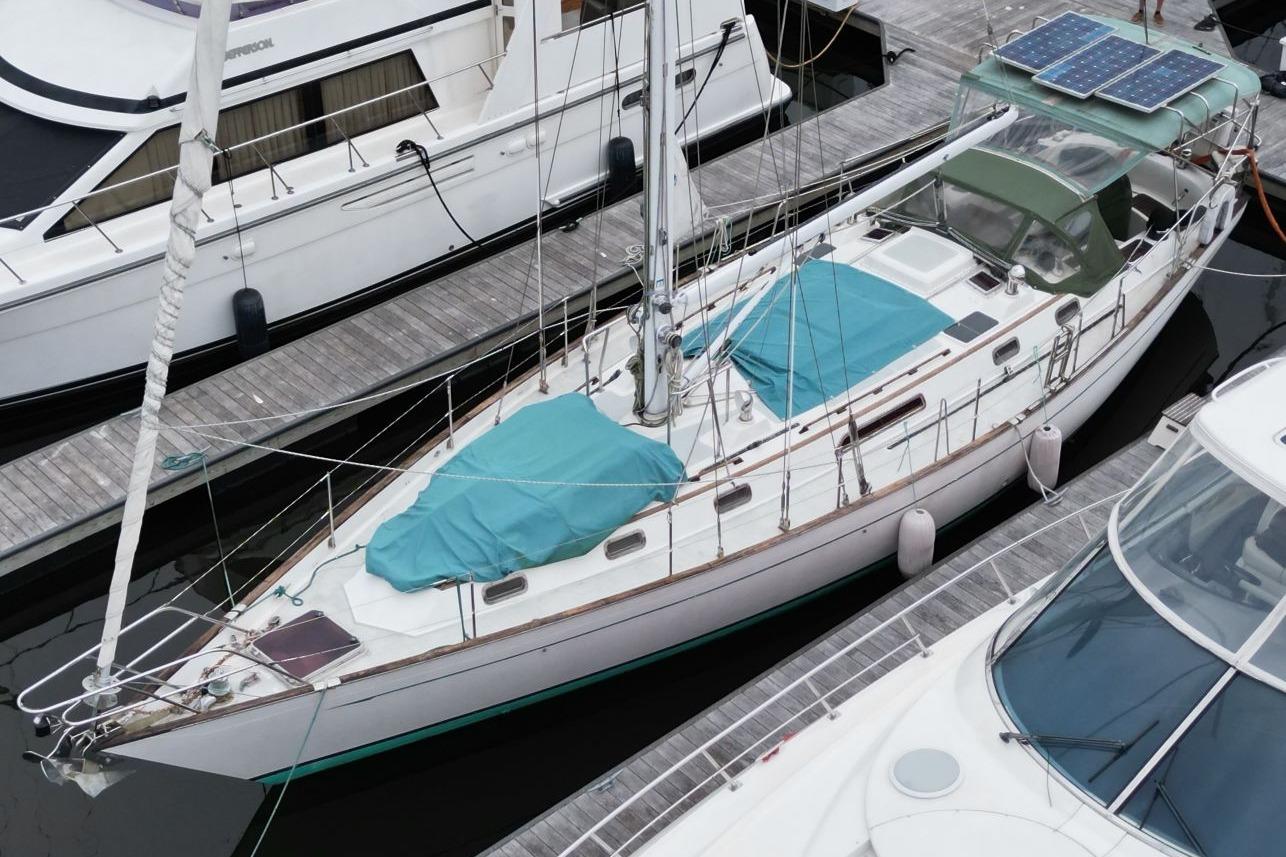 Passport 47 Sailboat docked at marina, Passport 47 model, 1985, with solar panels and teal covers.