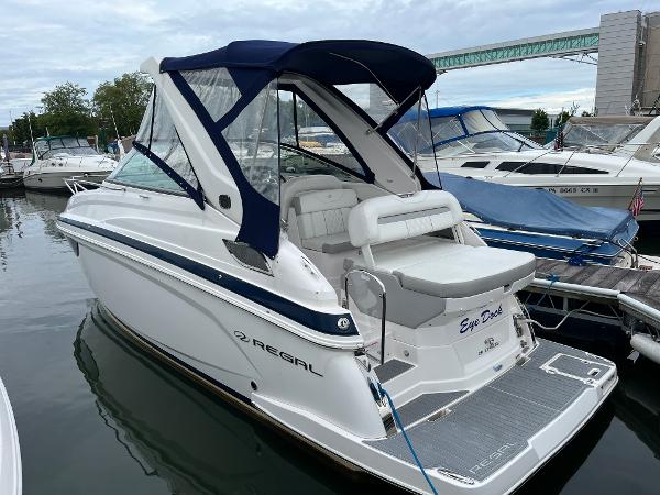 Regal 28 Express 2019 Regal 28 Express boat docked in marina, featuring sleek design and blue canopy.