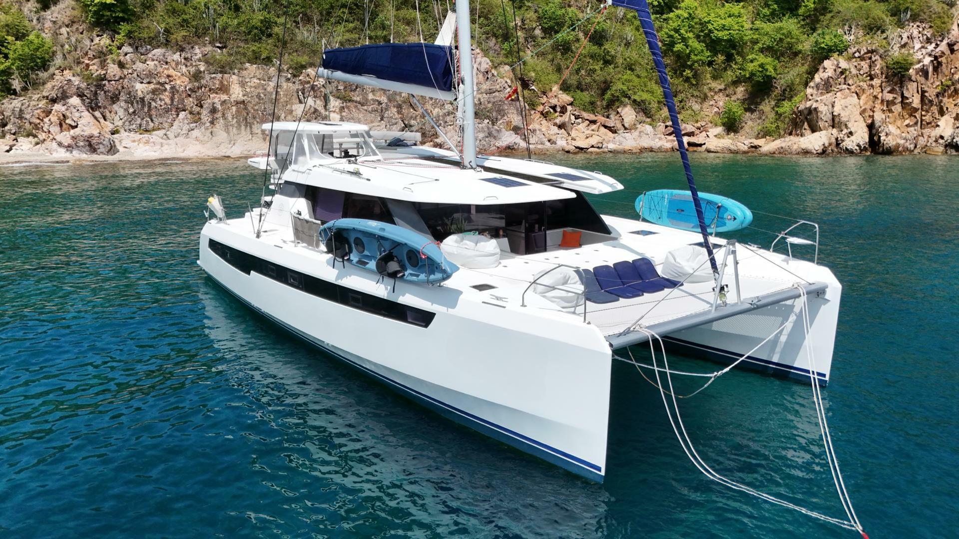 Leopard 50 Luxury Leopard 50 catamaran anchored in clear blue water near rocky shoreline, 2019 model.