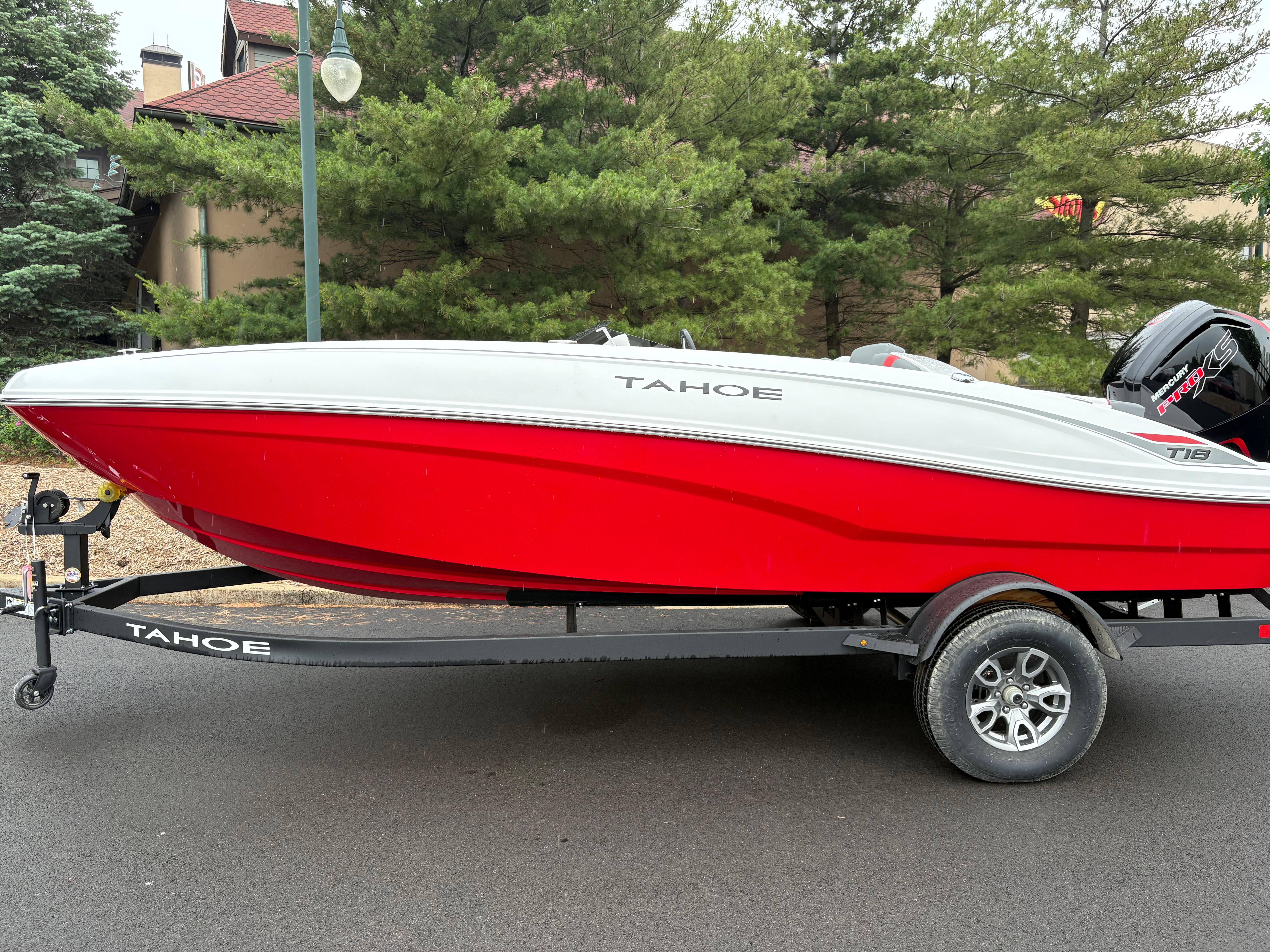 Tahoe T18 2025 Tahoe T18 boat in red and white on a trailer, parked outdoors.