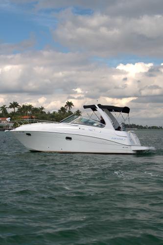 Four Winns Vista 2004 Four Winns Vista boat cruising on a lake under a cloudy sky.