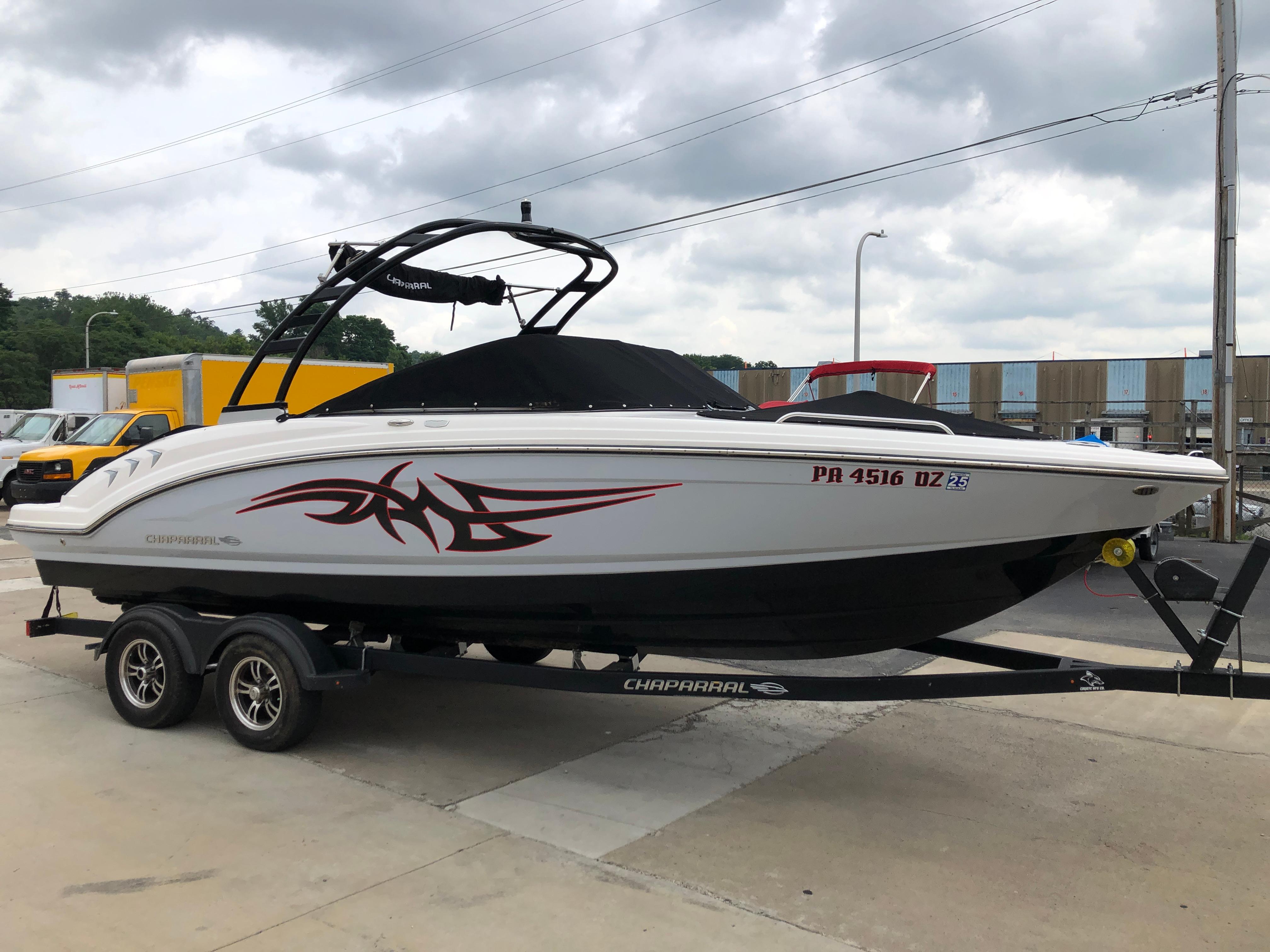 Chaparral 23 SSi 2021 Chaparral 23 SSi boat on trailer, white with red graphics, parked outdoors.