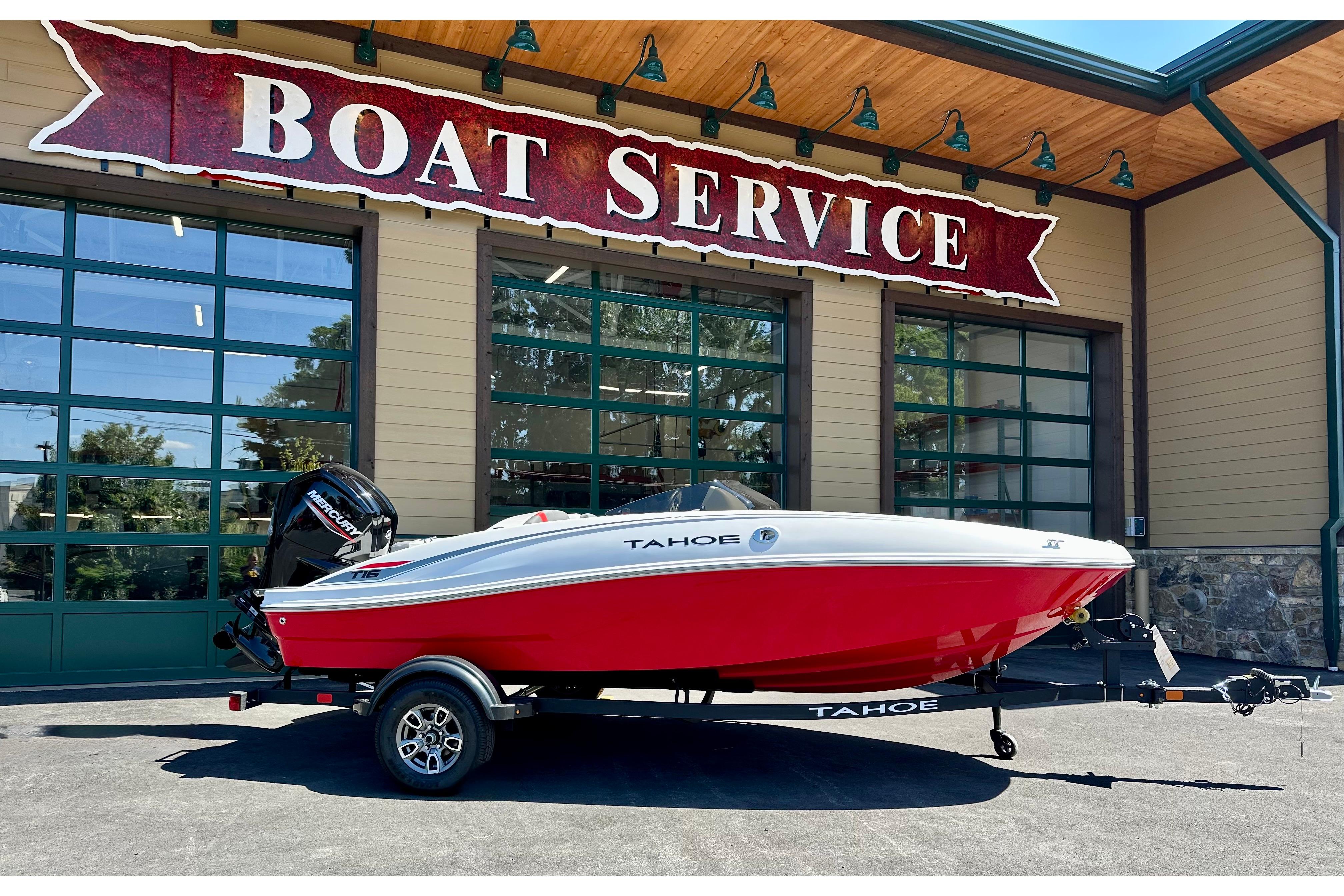 Tahoe T16 2025 Tahoe T16 boat in red, parked outside a boat service center.